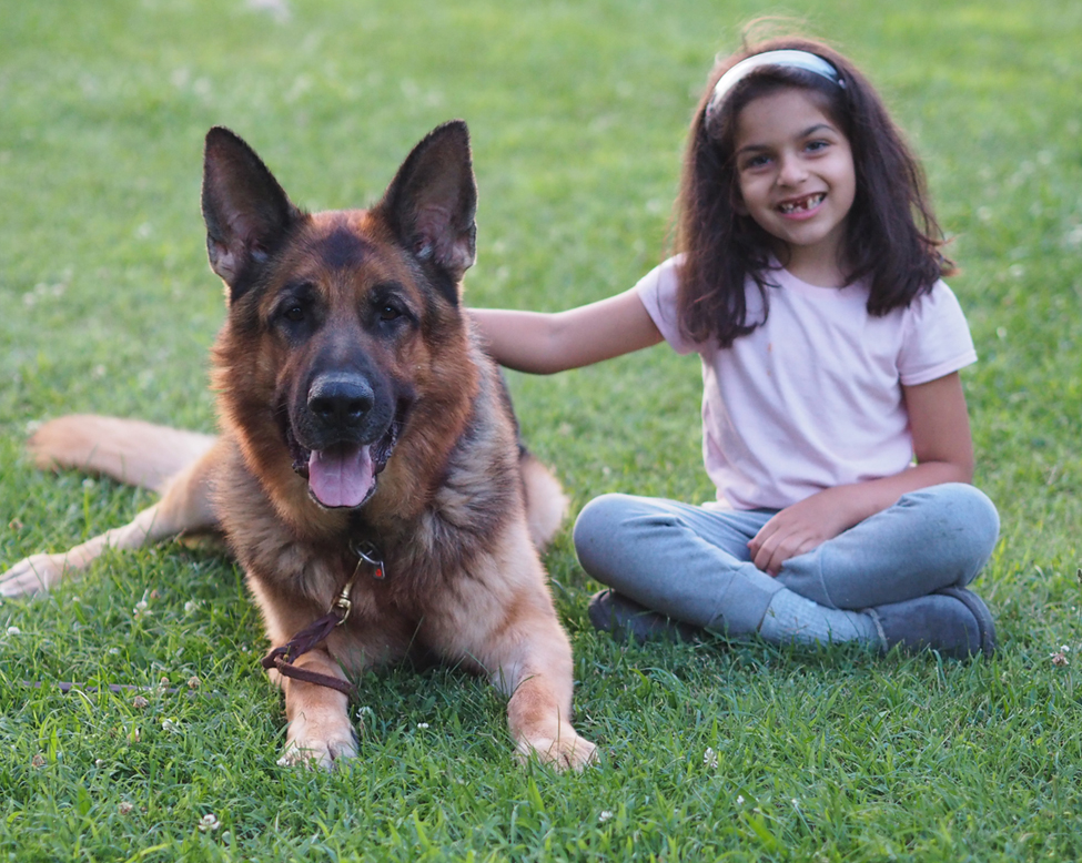 Atlas the german shepherd with a little girl sitting on the ground